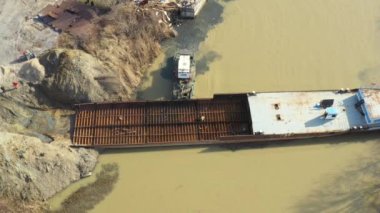 Üst manzarada, dolly kazı aracının, çekicinin ve römorkun üzerinde hareket ediyor. Eski yük gemisinin yatağının bir kısmını çekerken, mavna, nehir kıyısında, sersemletici, sökücü gemi, Scarp metali, geri dönüşüm....