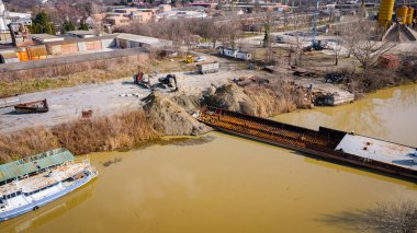 İşçiler eski büyük bir gemiyi keserken, mavnayı parçalara ayırırken, paslı metali kırbaç için keserken, asetilen meşalesi, geri dönüşüm, kıvılcımlar uçuşurken, üst görünümde işçiler görülüyor..