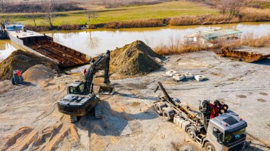 Manzaralı kazıcı ve çekicinin üstünde birlikte eski yük gemisinin yatağının bir kısmını çekiyorlar, mavna, nehir kıyısı, kazma, sökme gemisi, paslı metali kesme, geri dönüşüm....