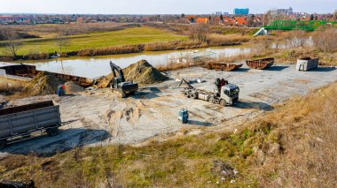 Manzaralı kazıcı ve çekicinin üstünde birlikte eski yük gemisinin yatağının bir kısmını çekiyorlar, mavna, nehir kıyısı, kazma, sökme gemisi, paslı metali kesme, geri dönüşüm....