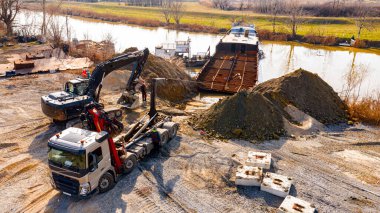 Manzaralı kazıcı ve çekicinin üstünde birlikte eski yük gemisinin yatağının bir kısmını çekiyorlar, mavna, nehir kıyısı, kazma, sökme gemisi, paslı metali kesme, geri dönüşüm....