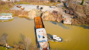 Kazıcının, çekicinin ve römorkörün üzerinde, eski yük gemisinin yatağının bir kısmını çekerken, mavna, nehir kıyısında, kazma, sökme gemisi, kırbaç için metal, geri dönüşüm,.