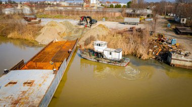 Kazıcının, çekicinin ve römorkörün üzerinde, eski yük gemisinin yatağının bir kısmını çekerken, mavna, nehir kıyısında, kazma, sökme gemisi, kırbaç için metal, geri dönüşüm,.