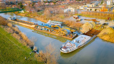 İşçiler eski büyük bir gemiyi keserken, mavnayı parçalara ayırırken, paslı metali kırbaç için keserken, asetilen meşalesi, geri dönüşüm, kıvılcımlar uçuşurken, üst görünümde işçiler görülüyor..