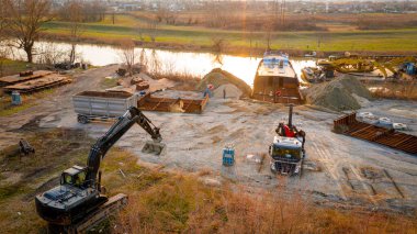 Manzaralı kazıcı ve çekicinin üstünde birlikte eski yük gemisinin yatağının bir kısmını çekiyorlar, mavna, nehir kıyısı, kazma, sökme gemisi, paslı metali kesme, geri dönüşüm....