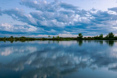 Akşamları güzel gün batımının manzarası gölün üzerinde, gölün üzerinde siluet suyun üzerinde ve bulutların üzerinde durduğu mavi gökyüzünün yansıması..