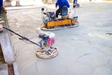 Two types of self-leveling power trowel machine with gas engine have wheels with pads, plate and he is driving it in circles smoothing surface on concrete slab. clipart