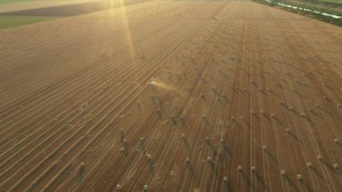 Dolly yukarıda, traktörün etrafındaki ışıkla yörüngeyi hareket ettirir. Pipeti yuvarlayan ve tarımsal alanın üzerine yuvarlanmış yuvarlak bir balya püskürten makine gibi..