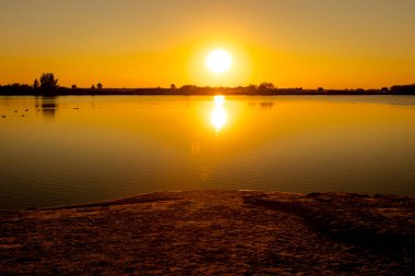 Akşamları güzel günbatımının manzarası gölün üzerinde, gölün üzerinde siluet suyun üzerinde ve bulutların sakin sularda yansıması.