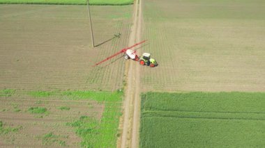 Manzaranın üstünde, bebek tarlaları ilaçlayana kadar traktör üzerinde hareket eder, tarlaya monte edilmiş geniş tarım püskürtücüleri sürükler yeni mısır, mısır, mısır, mısır....