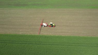 Manzaranın üstünde, bebek tarlaları ilaçlayana kadar traktör üzerinde hareket eder, tarlaya monte edilmiş geniş tarım püskürtücüleri sürükler yeni mısır, mısır, mısır, mısır....