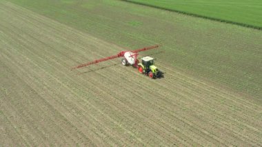 Manzaranın üstünde, bebek tarlaları ilaçlayana kadar traktör üzerinde hareket eder, tarlaya monte edilmiş geniş tarım püskürtücüleri sürükler yeni mısır, mısır, mısır, mısır....