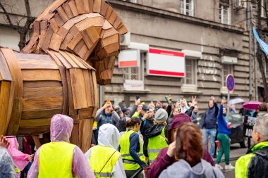 Sokaktaki protestocular, hükümet ve yolsuzluğu protesto etmek için Truva atı kalabalığını itiyor. Trajik bir kazada hayatını kaybedenler için adalet istiyorlar. Çatı çökmesi, tren istasyonu.