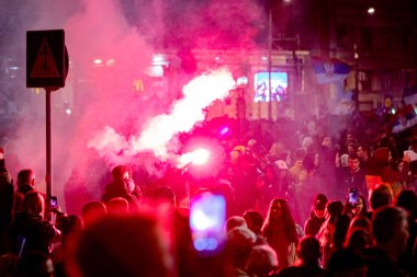 Belgrad, Sırbistan - 15 Mart 2025: Elinde yanan fişek tutan kalabalıktan bir adam, kırmızı meşaleyi mor, kırmızı duman çıkarırken yaktı. Öğrenciler, vatandaşlar hükümete ve rejime karşı protesto