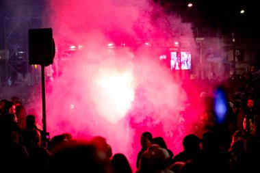 Belgrad, Sırbistan - 15 Mart 2025: Elinde yanan fişek tutan kalabalıktan bir adam, kırmızı meşaleyi mor, kırmızı duman çıkarırken yaktı. Öğrenciler, vatandaşlar hükümete ve rejime karşı protesto