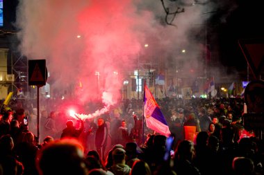 Belgrad, Sırbistan - 15 Mart 2025: Elinde yanan fişek tutan kalabalıktan bir adam, kırmızı meşaleyi mor, kırmızı duman çıkarırken yaktı. Öğrenciler, vatandaşlar hükümete ve rejime karşı protesto