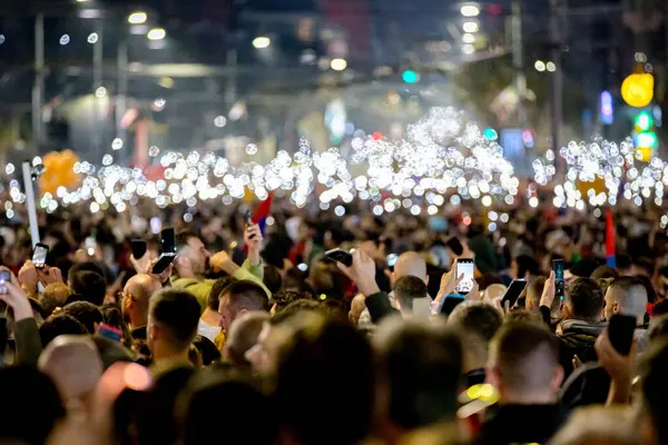 Belgrad, Sırbistan - 15 Mart 2025: Pek çok kişi cep telefonunu kaldırdı, cep telefonu el feneri kullandı, kurbanları onurlandırdı, 15 dakikalık saygı duruşunda bulundu