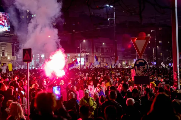 Belgrad, Sırbistan - 15 Mart 2025: Elinde yanan fişek tutan kalabalıktan bir adam, kırmızı meşaleyi mor, kırmızı duman çıkarırken yaktı. Öğrenciler, vatandaşlar hükümete ve rejime karşı protesto