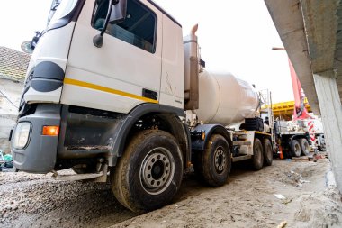 Karıştırıcı kamyonu inşaat alanında sevkiyat yapıyor. Rampadan kamyona pompa makinesiyle taze beton dökmek, beton dökmek, konut inşaatının somut temelleri için karışımı dağıtmak..