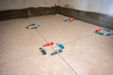 Konik plastik karo seviyelendirme sistem klipleri ve takozları aralarındaki boşluklu fayanslar arasında kurulum olarak seviyelendirme araçları yardımcı olur