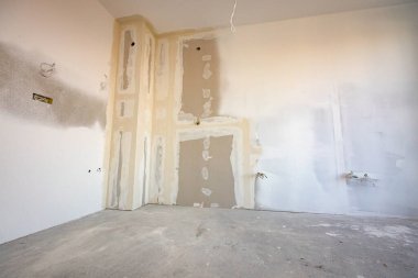 Köşesi, elektrik kabloları ve delikleri olan kahverengi alçıtaşının ön görüntüsü inşaat alanındaki inşaat halindeki binanın bölme duvarına tahtalar monte edilmiş..