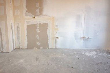 İnşaat alanında inşaat halindeki binanın bölme duvarına elektrik kabloları ve delikleri olan kahverengi alçı tahtalarının ön görüntüsü.