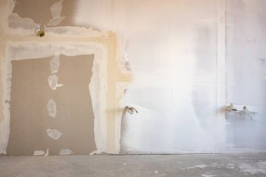 İnşaat alanında inşaat halindeki binanın bölme duvarına elektrik kabloları ve delikleri olan kahverengi alçı tahtalarının ön görüntüsü.