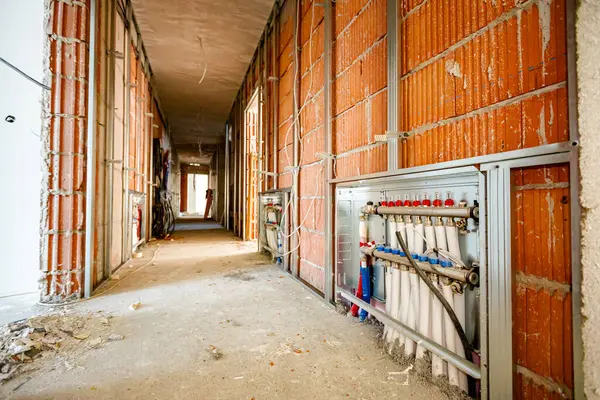 New brass distribution system manifold valves are mounted for central heating floor in a residential building under construction.