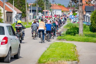 Polis memuru motosikletini tam üniformalı bir şekilde sürüyordu. Gruptaki insanları bisiklet sürerken, şehirde bisiklet sürerken, kalabalıkta sürüyordu. Trafikteki, kentsel çevredeki bisikletçiler için tehlike arz ediyordu.. 