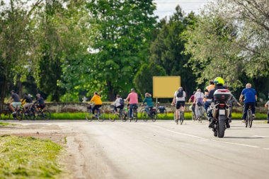 Polis memuru motosikletini tam üniformalı bir şekilde sürüyordu. Gruptaki insanları bisiklet sürerken, şehirde bisiklet sürerken, kalabalıkta sürüyordu. Trafikteki, kentsel çevredeki bisikletçiler için tehlike arz ediyordu.. 