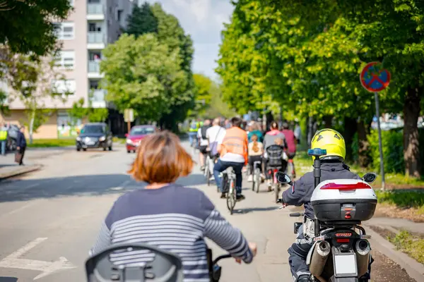 Polis memuru motosikletini tam üniformalı bir şekilde sürüyordu. Gruptaki insanları bisiklet sürerken, şehirde bisiklet sürerken, kalabalıkta sürüyordu. Trafikteki, kentsel çevredeki bisikletçiler için tehlike arz ediyordu.. 