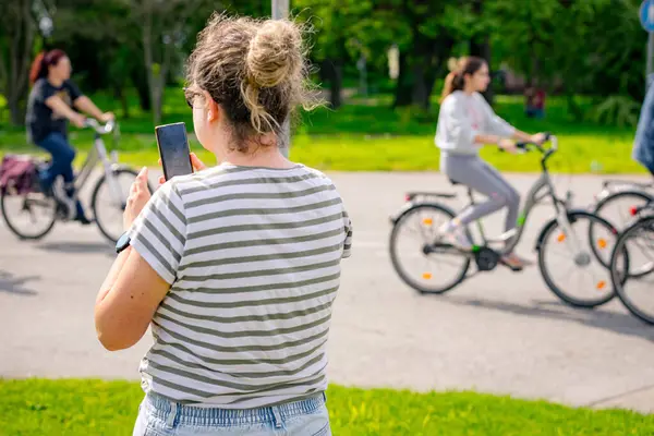 Kadın, bisiklet süren, bisiklet süren, kalabalık içinde araba kullanan insanlardan oluşan bir grupla fotoğraf çekiyor. Trafikte, kentsel çevrede bisikletçiler için tehlikelere dikkat çekmeye çalışıyorlar.. 