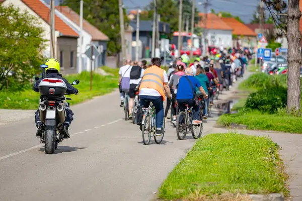 Polis memuru motosikletini tam üniformalı bir şekilde sürüyordu. Gruptaki insanları bisiklet sürerken, şehirde bisiklet sürerken, kalabalıkta sürüyordu. Trafikteki, kentsel çevredeki bisikletçiler için tehlike arz ediyordu.. 