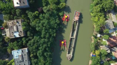 En tepedeki manzarada, kule iki kazıcının üzerinden uçar. Nehir, kanal, tortuları derinleştirir ve temizler. Kirli bir su yolundaki çamurdan arınırlar..