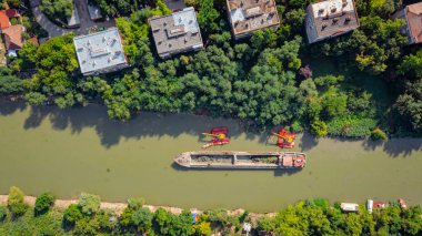 Nehir, kanal, derinleştirme ve kirli bir su yolundaki tortu, çamur, nehir yatağından kaldırma üzerine çalışan iki kazıcının üzerinde tepenin üstündeler..