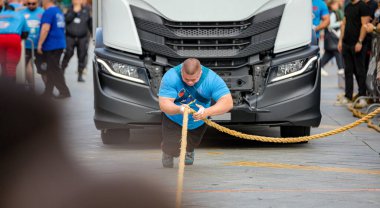 Güçlü atlet, kaslı vücut geliştirici, güçlü adam müsabakalarında, güçlü ekstrem sporlarda yarışan, kararlı ve gayretli bir şekilde kamyonu çekiyor..