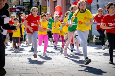 Zrenjanin, Voyvodina, Sırbistan - 25 Mayıs 2025: Geniş bir grup çocuk, sporcular bir sokak maratonunda koşuyor, kalabalık şehir yarışında koşuyor.