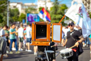 Fotoğrafçı insanların fotoğraflarını çekiyor, ahşap ve metalden yapılmış eski model retro kamera kullanıyor, ahşap kutu tasarımı, modern profesyonel tripodlar üzerinde kentsel alandaki halk etkinliklerinde,.
