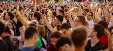 Bulanık, belirsiz pek çok insan el kaldırıyor cep telefonu, fenerli cep telefonu, kurbanları onurlandıran ışık, Sırbistan 'da çatı çökmesi ve tren istasyonunda kaybedilen hayatlar için 16 dakikalık sessizlik.