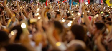 Bulanık, belirsiz pek çok insan el kaldırıyor cep telefonu, fenerli cep telefonu, kurbanları onurlandıran ışık, Sırbistan 'da çatı çökmesi ve tren istasyonunda kaybedilen hayatlar için 16 dakikalık sessizlik.