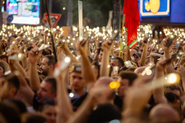 Bulanık, belirsiz pek çok insan el kaldırıyor cep telefonu, fenerli cep telefonu, kurbanları onurlandıran ışık, Sırbistan 'da çatı çökmesi ve tren istasyonunda kaybedilen hayatlar için 16 dakikalık sessizlik.