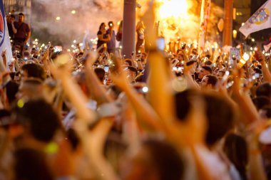 Bulanık, belirsiz pek çok insan el kaldırıyor cep telefonu, fenerli cep telefonu, kurbanları onurlandıran ışık, Sırbistan 'da çatı çökmesi ve tren istasyonunda kaybedilen hayatlar için 16 dakikalık sessizlik.