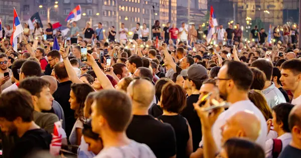 Bulanık, belirsiz pek çok insan el kaldırıyor cep telefonu, fenerli cep telefonu, kurbanları onurlandıran ışık, Sırbistan 'da çatı çökmesi ve tren istasyonunda kaybedilen hayatlar için 16 dakikalık sessizlik.