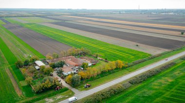 Manzaranın üstünde, çimlerin üzerinden çim biçme makinesini çekerken iki traktör, asfalt yolun yanındaki çiftlik evini, çiftliği biçerken....