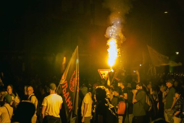 Novi Sad, Voyvodina, Sırbistan - 05 Eylül 2025: Elinde yanan işaret fişeği tutan kalabalıktan bir adam, sarı meşaleyi yaktı ve duman çıkardı. Öğrenciler ve vatandaşlar rejimi protesto ediyorlar 16 kişinin hayatını kaybetmesi için adalet talep ediyorlar 