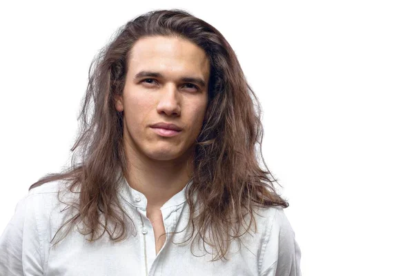 Handsome calm man. Portrait of a young muscular guy with long hair. Strong boy on an isolated grey background in the studio