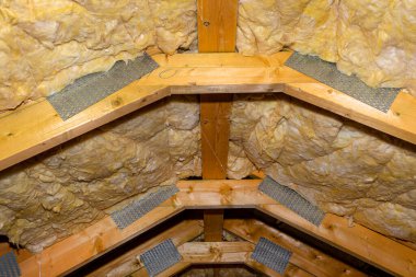Insulation of walls and ceiling in the attic made of mineral wool between trusses, tied with polypropylene string. clipart