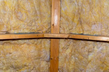 Çatı katında kirişler arasındaki mineral yünden yapılmış duvar ve tavan izolasyonu, polipropilen iplikle bağlanmış..