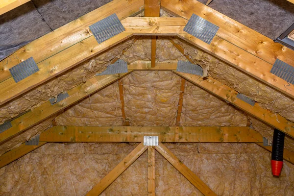 Insulation of walls and ceiling in the attic made of mineral wool between trusses, tied with polypropylene string.