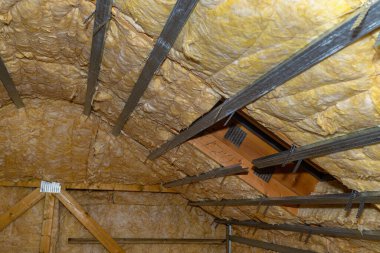 Aluminum frame with hangers placed on beams in the attic for mounting plasterboards, visible roof window.